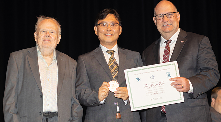 Kim awarded medal and certificate on stage from Dr. Hawkinson and Dr. Chambliss.