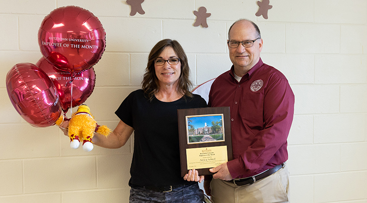 Schuck accepting award plaque and balloons from President.