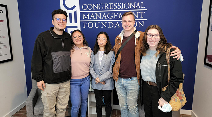 Students standing in front of blue wall.