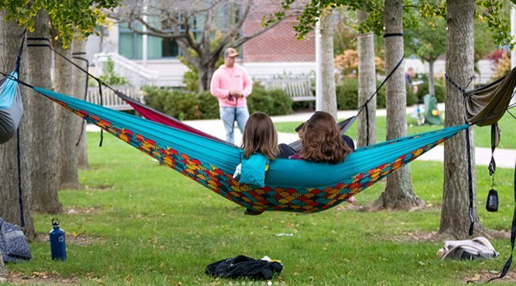 Students sitting in hammock outside.