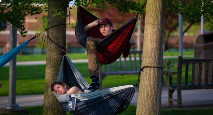 A photo two students in lounging in hammocks