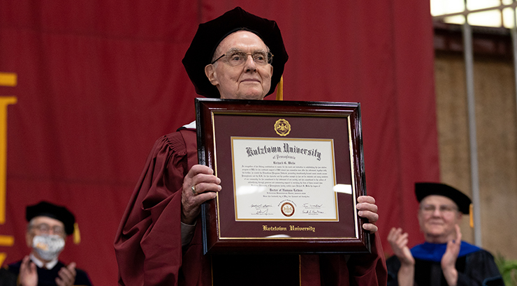 Wells holding diploma on stage.