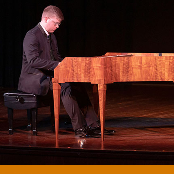 Image of a male sitting at a piano