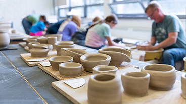 Male art education major at Kutztown University leading a pottery class with students.