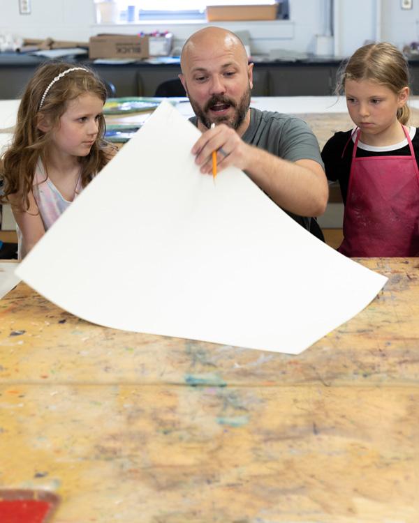 Art Education Major at Kutztown University working with two young students in art classroom.