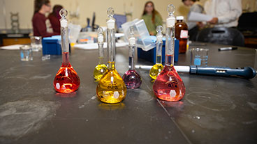 Chemistry degree lab space with colorful solutions in beakers on lab table.