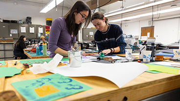 Two students pursuing graphic design degree working on a project in the Sharadin Arts Building.