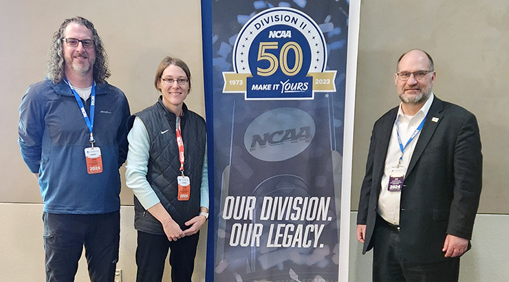 Leaders standing next to NCAA floor banner