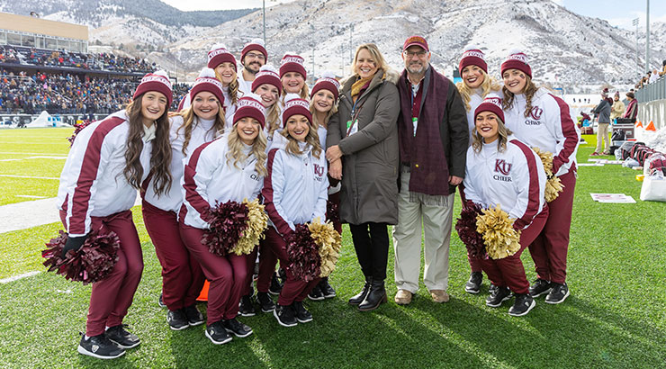 President Hawkinson and Ann Marie Hawkinson surrounded by cheerleaders in Co. 