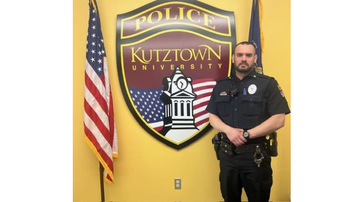 Officer Lukens with KUPD badge on wall in background