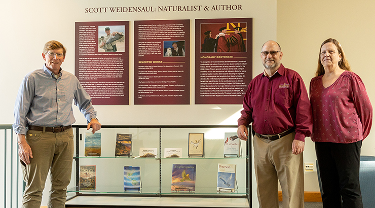 Weidensaul, Hawkinson and Stevenson posing for photo next to exhibit