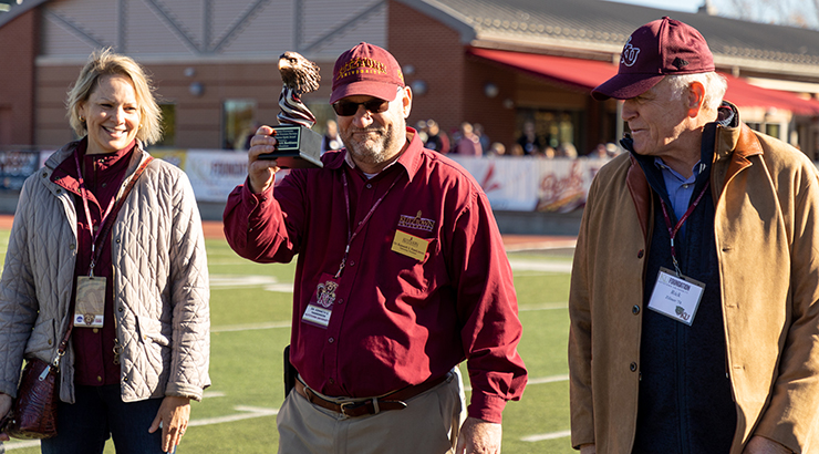 President Hawkinson holding 2024 Veteran Spirit trophy with Mrs. Hayes-Hawkinson and Veteran.