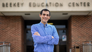 Education Doctorate student from Kutztown University standing with arms folded in front of Beekey Education building.