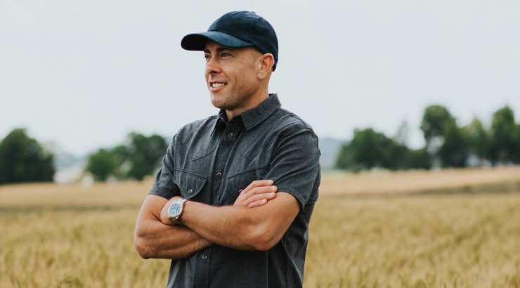 Jeff Tkack standing in a field with his arms crossed looking out to the distance