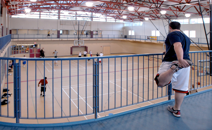 Overhead shot of the basketball court with a male student stretching on the catwalk in the foreground