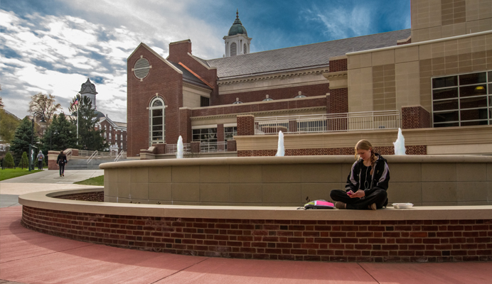 Female student sitting on the fountain in Marcon Plaza 