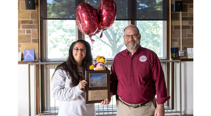 Mishra (left) accepting award plaque and balloons from President Hawkinson (right)