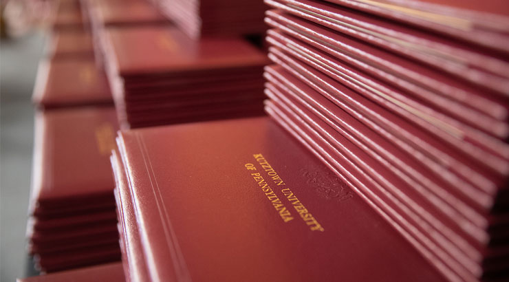 A stack of maroon diploma covers, each with the words Kutztown University of Pennsylvania.