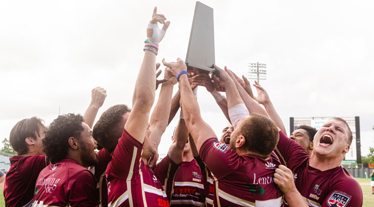 Rugby players hold trophy aloft in celebration
