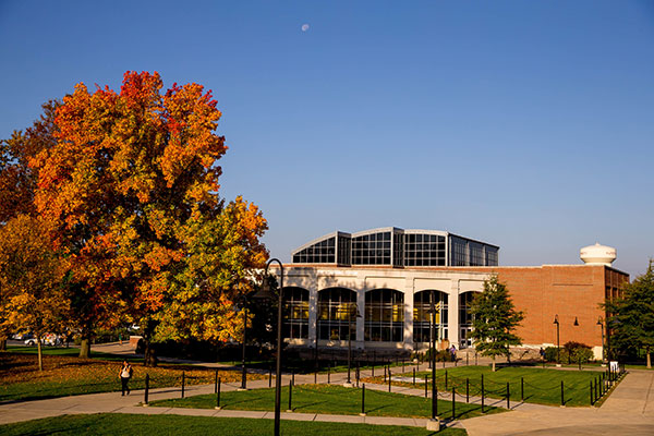 The exterior of the academic forum on a fall day with green grass and vibrant fall foliage on the trees set against a clear blue sky.