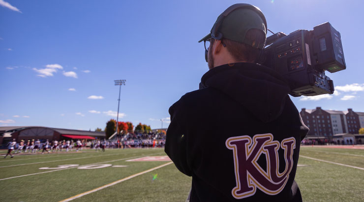 Kutztown University film major capturing sporting event on football field.