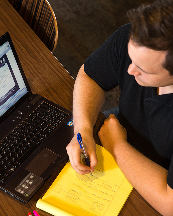 student taking notes and working on computer