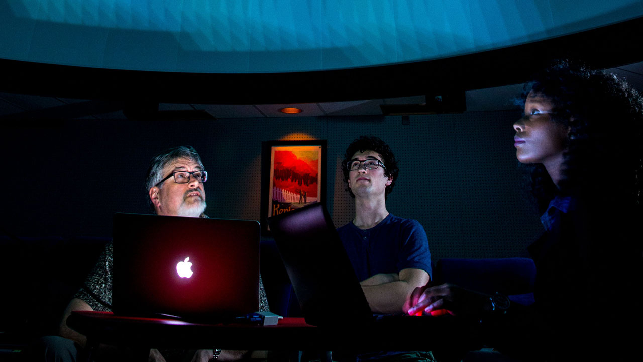 Professor and two students working on computer program in planetarium