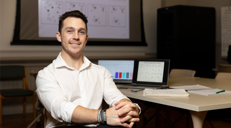 Male student pursuing data science degree at Kutztown University sits at desk and takes notes from his computer.