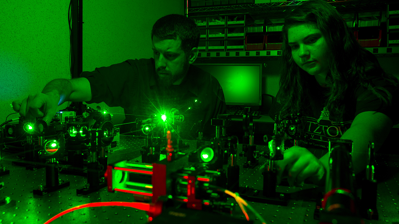 Professor and student working together on a green laser in a dark room