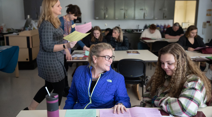 Two female students in KU classroom discussing project within their sociology degree.