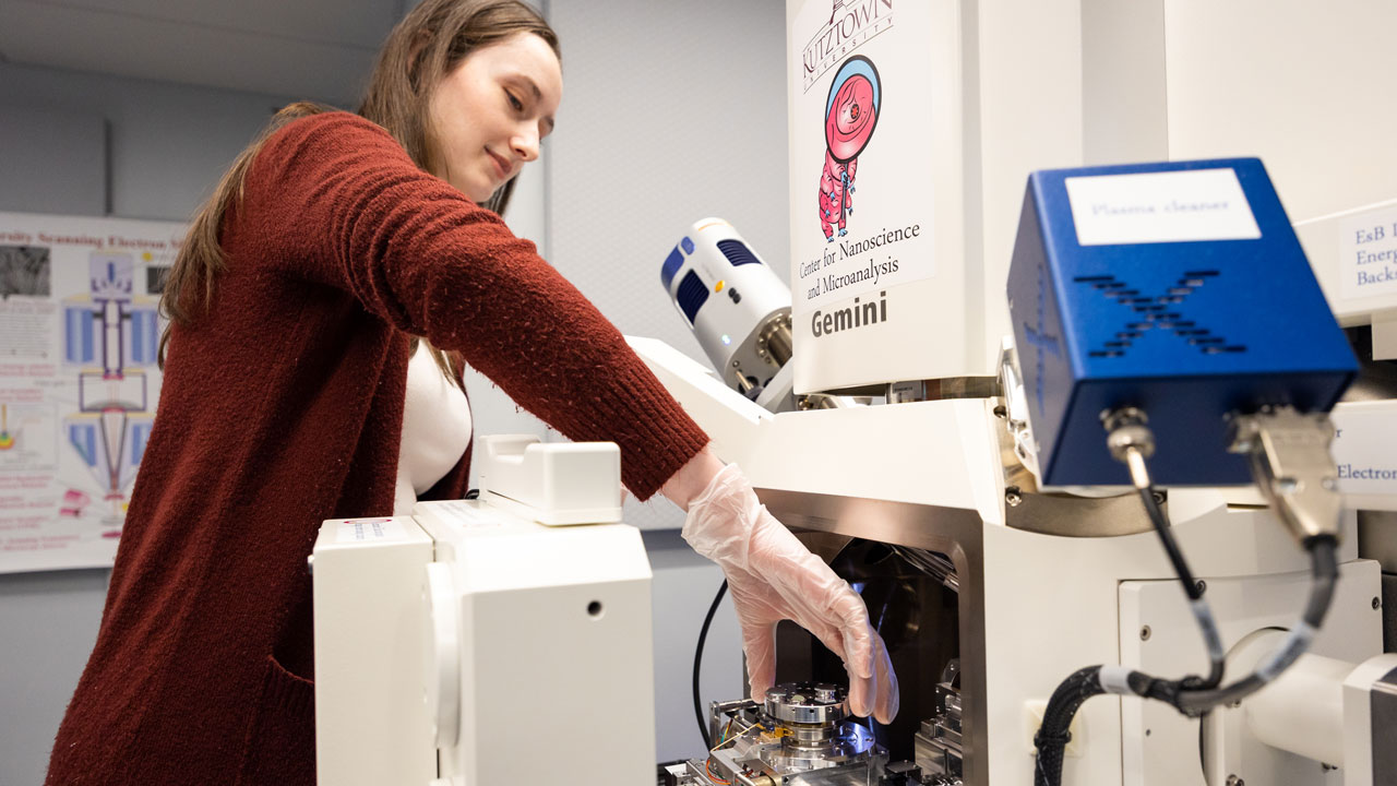 Female student adjusts the Scanning Electron Microscope