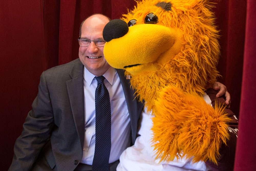 President Hawkinson poses with Avalanche the golden bear for a photo in a photobooth